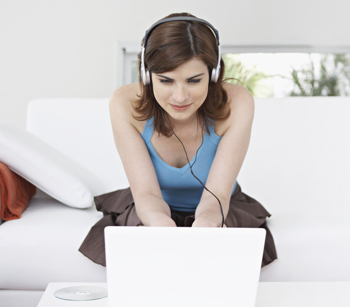 Frau sitzend auf einer Couch vor einem Laptop Frau sitzend auf einer Couch vor einem Laptop